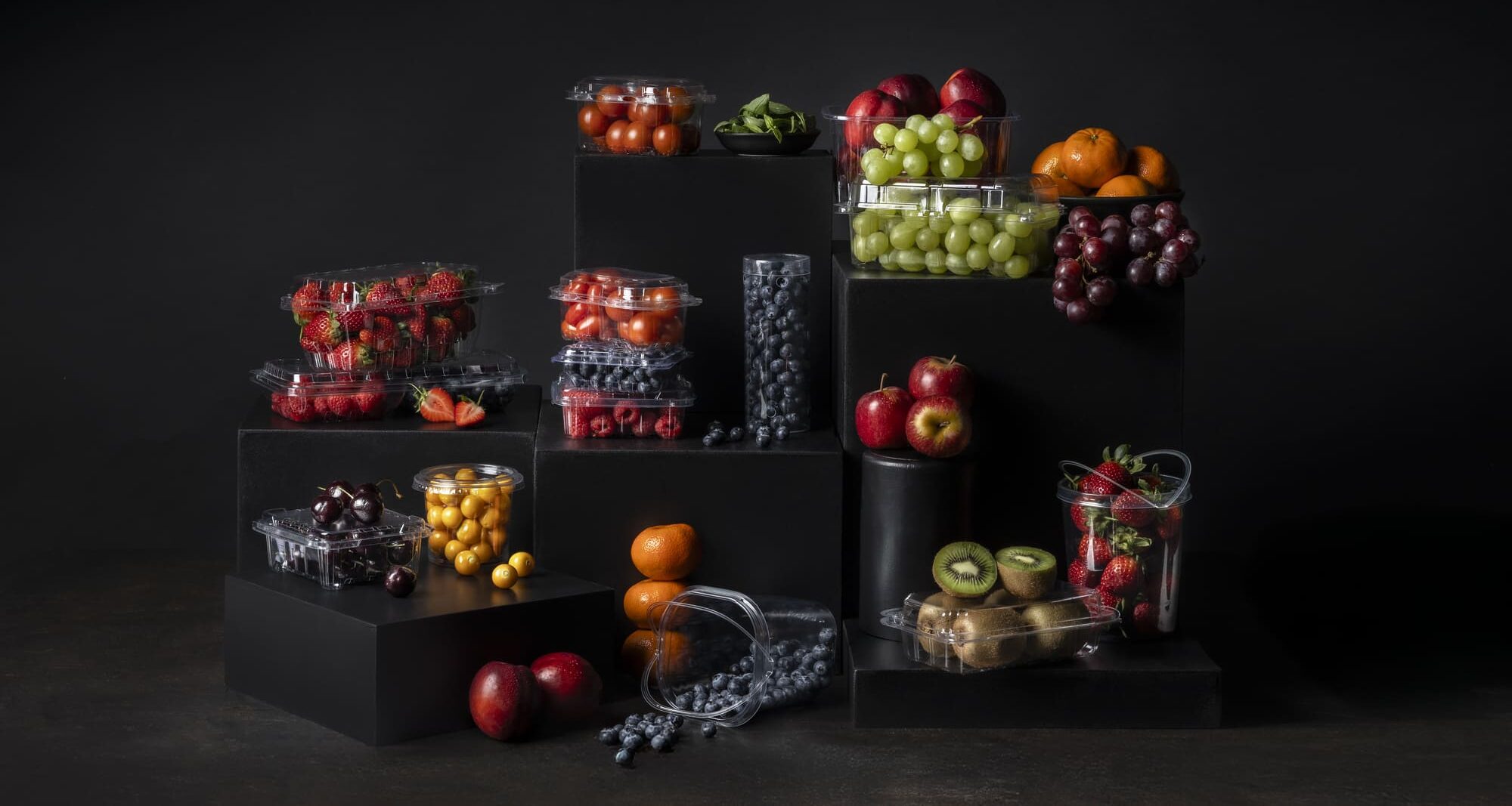 Black pedestals showcasing agricultural fruit and vegetable packaging containers.
