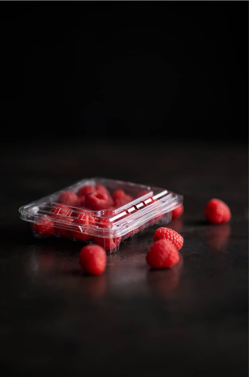 A snack sized Yucca Packaging punnet clamshell container packed with raspberries.