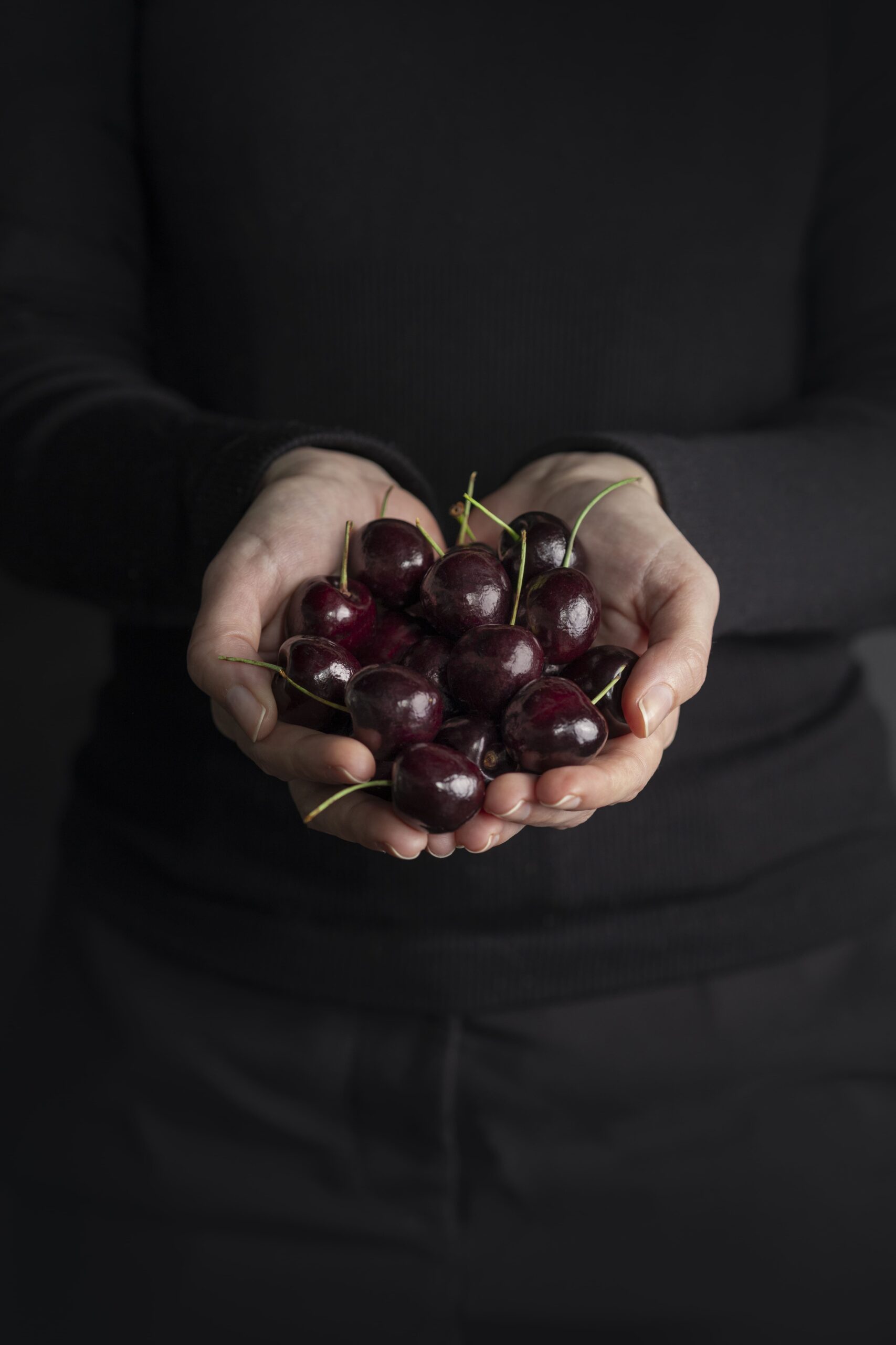 Cherries held in hands reaching out to you.