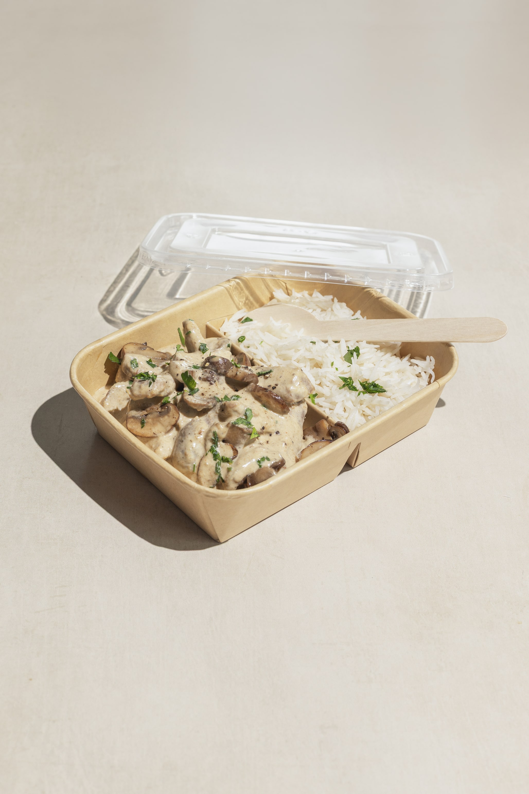 Yucca Packaging kraft paper portion 2/D bowl & lid filled with creamy mushroom pasta and rice.